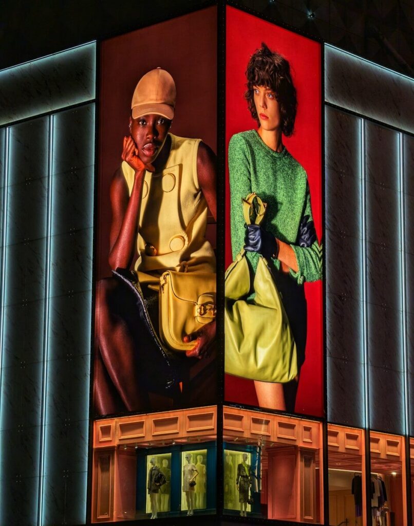 Two women modeling fashion on a building facade